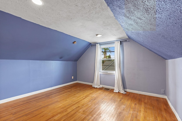 3204 Mcguffey Rd, Columbus, OH 43224 - additional living space with baseboards, hardwood / wood-style floors, a textured ceiling, and vaulted ceiling