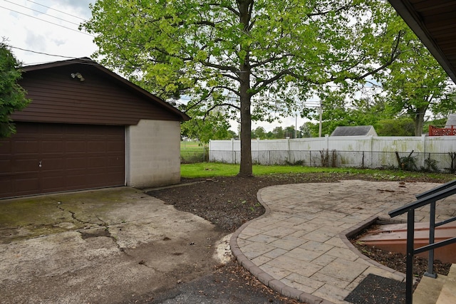 view of yard featuring fence, an outdoor structure, a garage, and concrete driveway