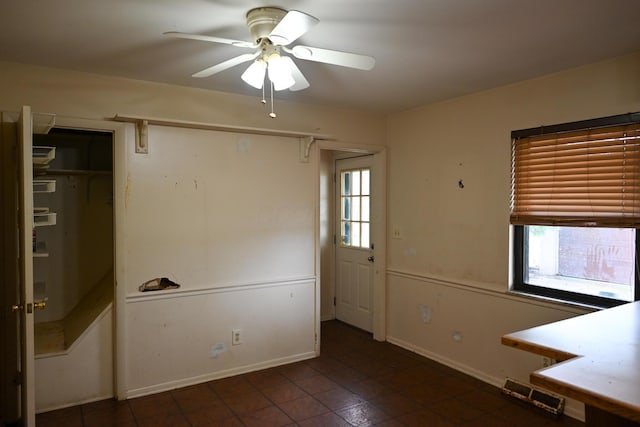 unfurnished dining area with ceiling fan, baseboards, and tile patterned floors