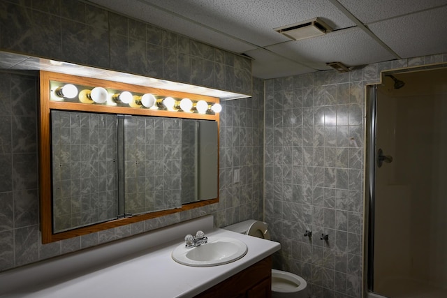 bathroom with a stall shower, tile walls, vanity, and toilet