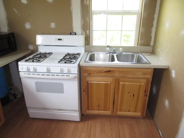 6800 Center Rd, Philo, OH 43771 - kitchen with white range with gas cooktop, a sink, black microwave, light wood-type flooring, and light countertops