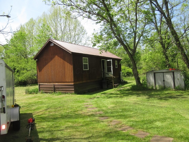 6800 Center Rd, Philo, OH 43771 - view of side of property with a storage unit, a lawn, an outdoor structure, and metal roof