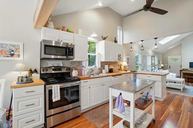 286 Rosslyn Ave, Columbus, OH 43214 - kitchen with stainless steel appliances, a sink, high vaulted ceiling, light wood finished floors, and a peninsula