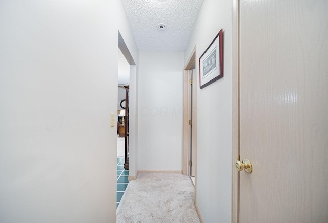 hall featuring carpet flooring and a textured ceiling