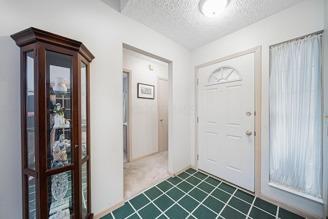 entrance foyer with dark carpet, a textured ceiling, and baseboards
