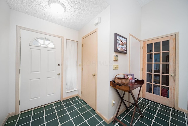 entrance foyer with a textured ceiling, tile patterned flooring, and baseboards