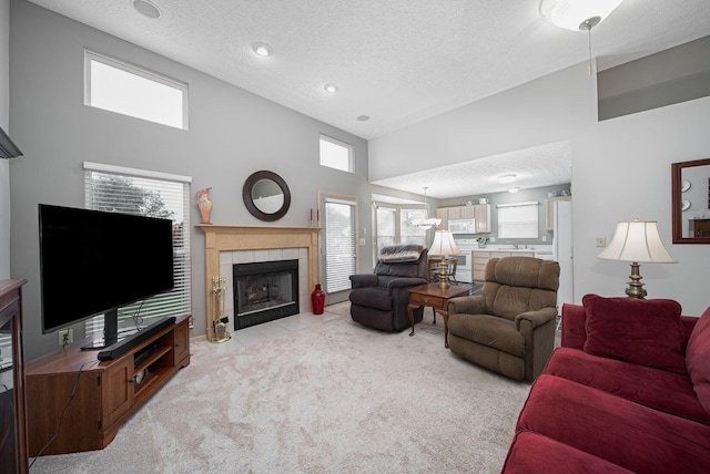 living area featuring a textured ceiling, a tile fireplace, light colored carpet, and a high ceiling