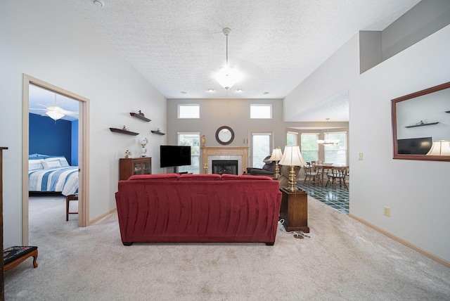 carpeted living room featuring a ceiling fan, a textured ceiling, a fireplace, and baseboards