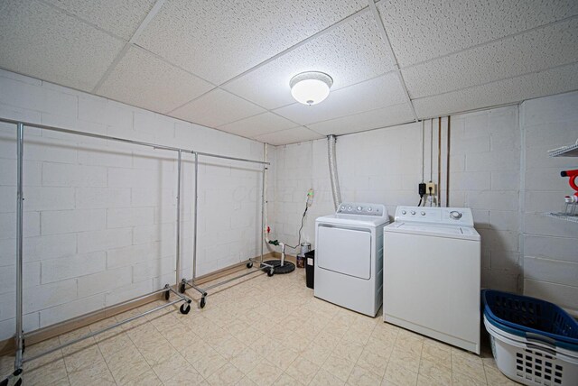laundry area featuring washing machine and clothes dryer, concrete block wall, and tile patterned floors
