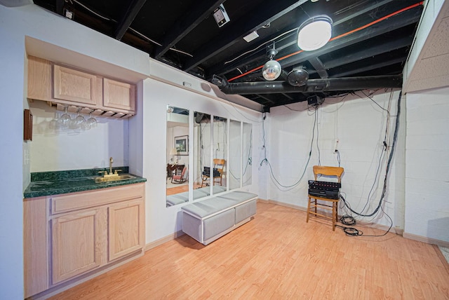 basement featuring bar with sink and light wood finished floors