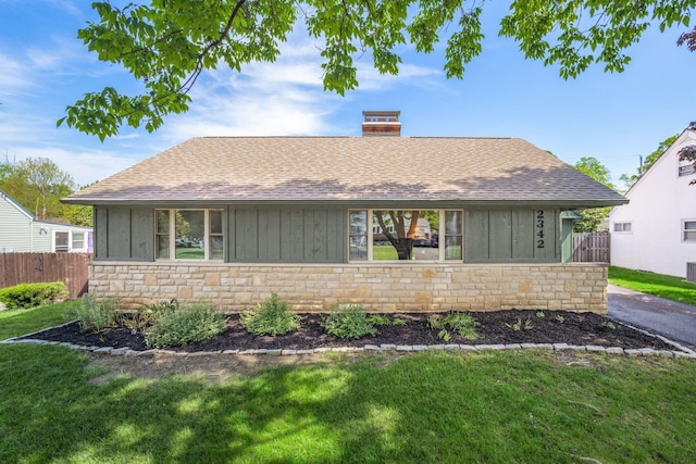view of front of house featuring board and batten siding, stone siding, a shingled roof, and a chimney