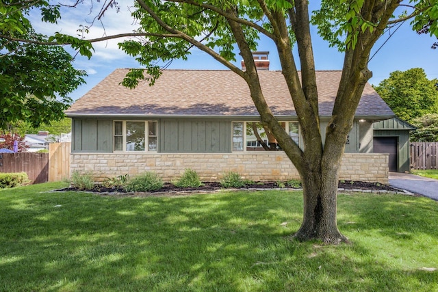 view of front of home with roof with shingles, stone siding, a chimney, board and batten siding, and asphalt driveway