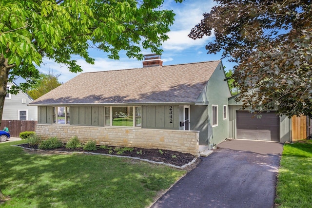 english style home featuring a shingled roof, asphalt driveway, board and batten siding, and a chimney
