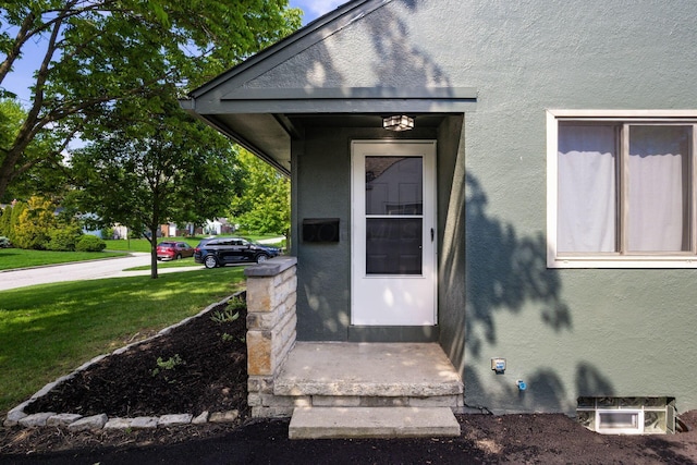 property entrance featuring stucco siding and a lawn