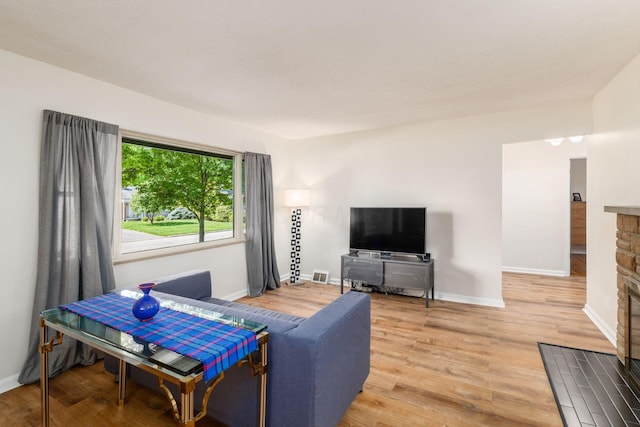 living area featuring wood finished floors, baseboards, and a fireplace