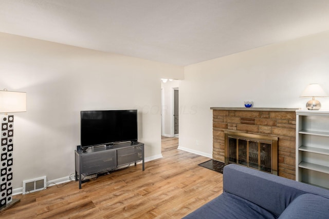 living area with wood finished floors, a fireplace, and baseboards