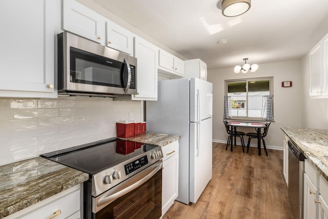 kitchen featuring appliances with stainless steel finishes, backsplash, white cabinets, light wood finished floors, and light stone countertops