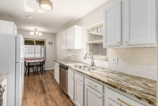 kitchen with freestanding refrigerator, dishwasher, a sink, white cabinetry, and backsplash