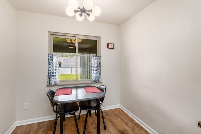 dining space with a chandelier, wood finished floors, and baseboards
