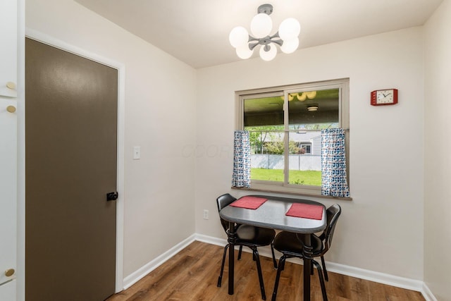 dining area featuring a chandelier, baseboards, and wood finished floors