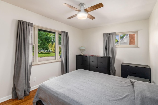 bedroom with wood finished floors, baseboards, and a ceiling fan