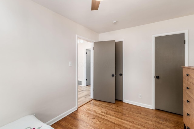 unfurnished bedroom featuring baseboards, light wood-style flooring, and a ceiling fan