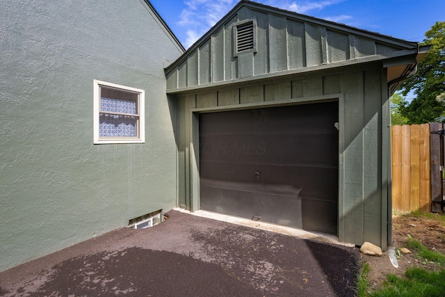 garage featuring fence and driveway