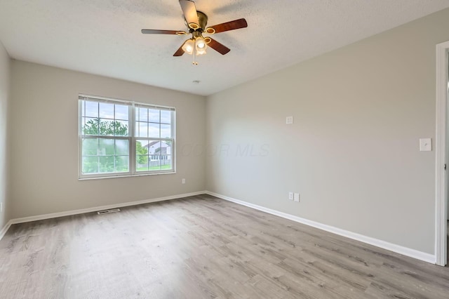 spare room with wood finished floors, baseboards, a ceiling fan, and a textured ceiling