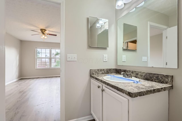 bathroom featuring a ceiling fan, wood finished floors, vanity, and baseboards