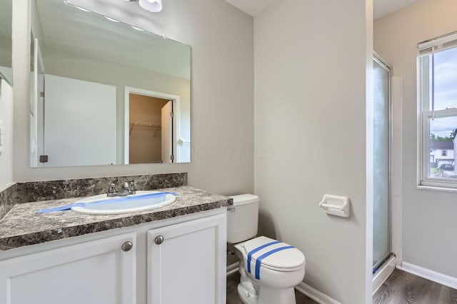 bathroom featuring a stall shower, toilet, vanity, baseboards, and wood finished floors