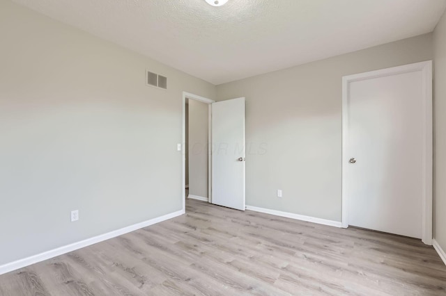 unfurnished bedroom featuring wood finished floors, baseboards, and a textured ceiling