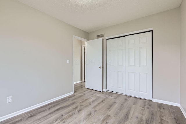 unfurnished bedroom featuring light wood-style floors, baseboards, and a closet