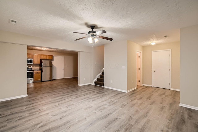 3983 Summerstone Dr, Columbus, OH 43230 - unfurnished living room featuring a ceiling fan, light wood-type flooring, stairs, a textured ceiling, and baseboards