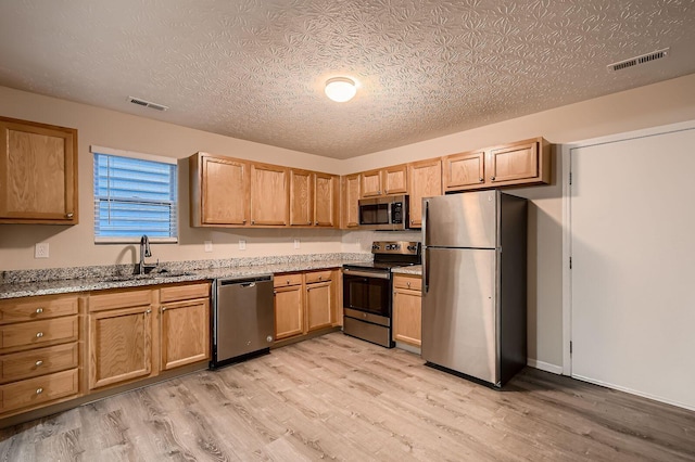 3983 Summerstone Dr, Columbus, OH 43230 - kitchen with stainless steel appliances, a sink, light wood finished floors, light stone counters, and a textured ceiling