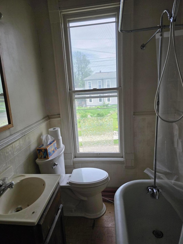 195 N Monroe Ave, Columbus, OH 43203 - bathroom with tile walls, a soaking tub, vanity, a wainscoted wall, and toilet