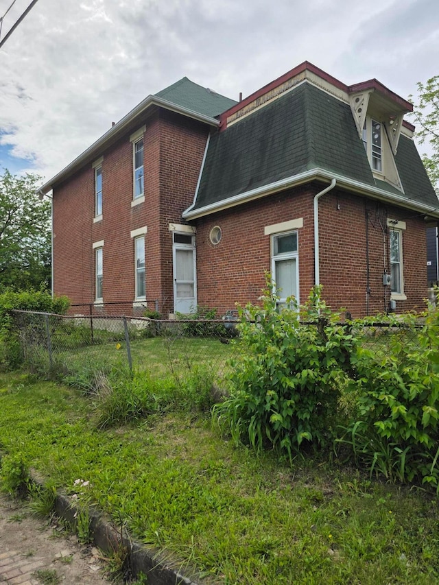 195 N Monroe Ave, Columbus, OH 43203 - view of side of property with brick siding, fence, a shingled roof, and mansard roof