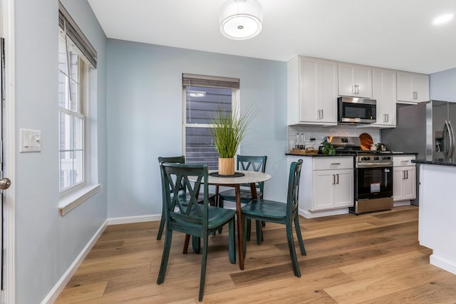 225 Reeb Ave, Columbus, OH 43207 - kitchen with stainless steel appliances, dark countertops, tasteful backsplash, light wood-style flooring, and white cabinetry