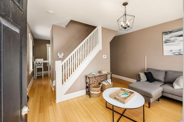 living room featuring stairs, wood finished floors, a chandelier, and baseboards