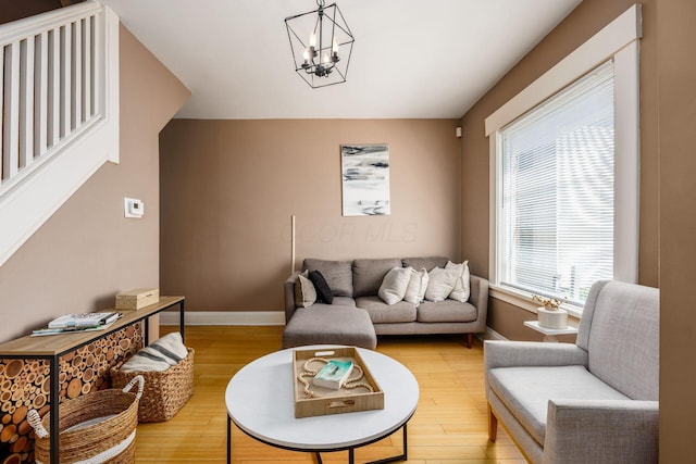 living room with baseboards, light wood finished floors, and a chandelier