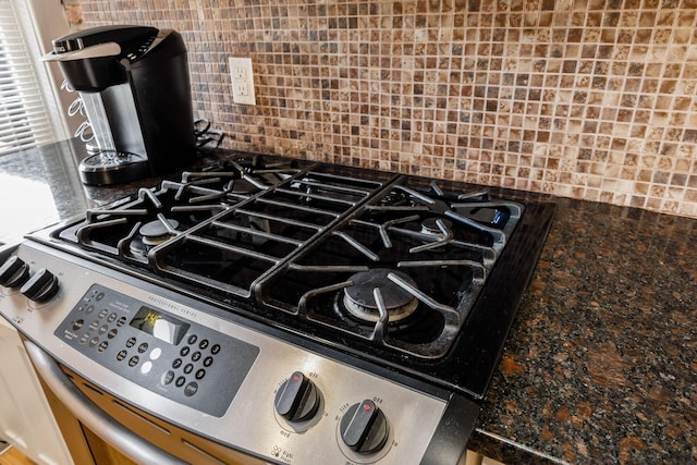 kitchen view of tasteful backsplash, stainless steel range with gas stovetop, and dark countertops