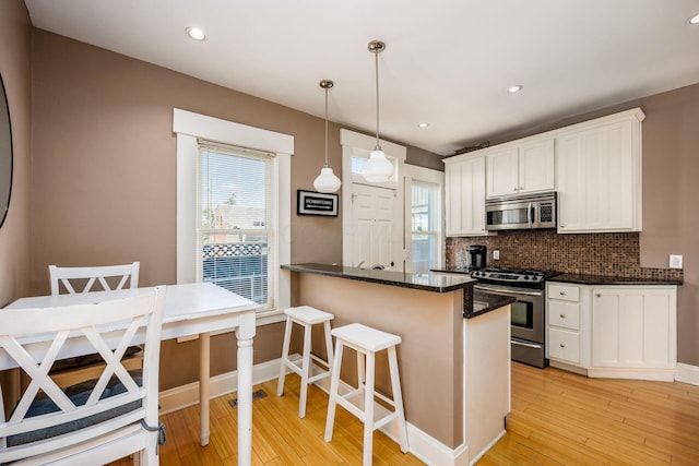 kitchen with stainless steel appliances, light wood-style flooring, tasteful backsplash, white cabinets, and healthy amount of natural light