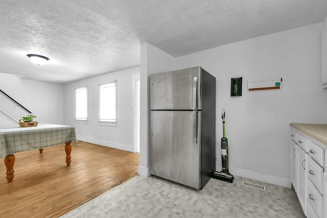 221 W Mulberry St, Baltimore, OH 43105 - kitchen with freestanding refrigerator, white cabinetry, baseboards, a textured ceiling, and light flooring