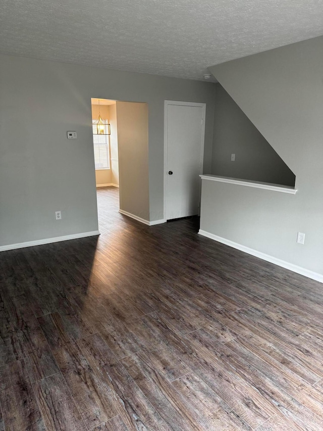 5076 Dalmeny Ct, Columbus, OH 43220 - unfurnished living room with dark wood-type flooring, a chandelier, a textured ceiling, and baseboards