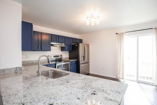 960 Hartford Village Blvd, Columbus, OH 43228 - kitchen featuring stainless steel appliances, a sink, under cabinet range hood, light stone countertops, and blue cabinetry