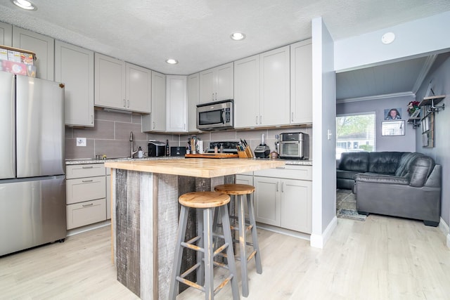 2806 Claude Dr, Columbus, OH 43207 - kitchen with stainless steel appliances, light wood finished floors, a breakfast bar, recessed lighting, and backsplash