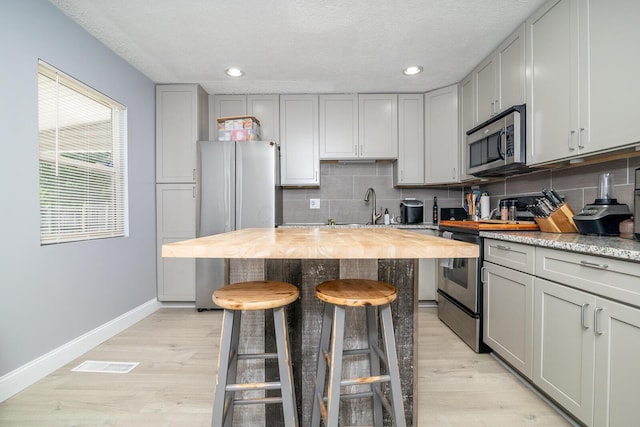 2806 Claude Dr, Columbus, OH 43207 - kitchen with stainless steel appliances, gray cabinets, baseboards, tasteful backsplash, and a textured ceiling