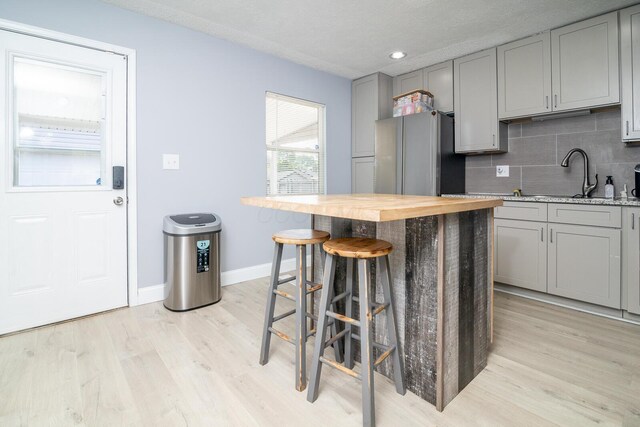 2806 Claude Dr, Columbus, OH 43207 - kitchen featuring gray cabinets, freestanding refrigerator, light wood-type flooring, butcher block countertops, and decorative backsplash