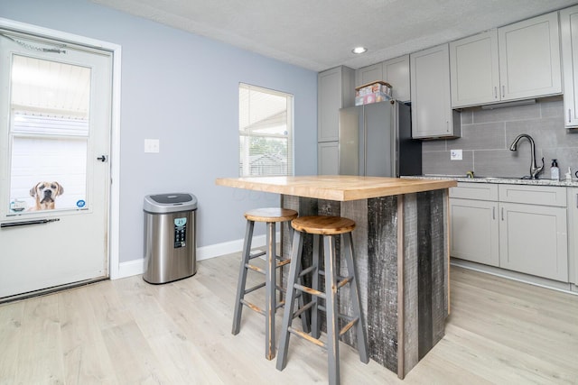 2806 Claude Dr, Columbus, OH 43207 - kitchen featuring freestanding refrigerator, gray cabinets, light wood-type flooring, backsplash, and a textured ceiling