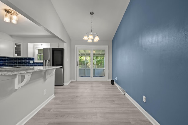 4187 Medway Ave, Columbus, OH 43213 - unfurnished dining area featuring a chandelier, vaulted ceiling, light wood-style flooring, and baseboards