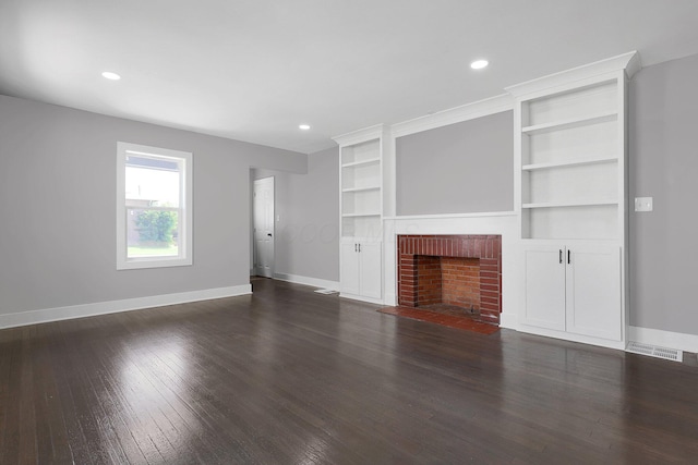 unfurnished living room with baseboards, dark wood-style flooring, a brick fireplace, recessed lighting, and built in shelves